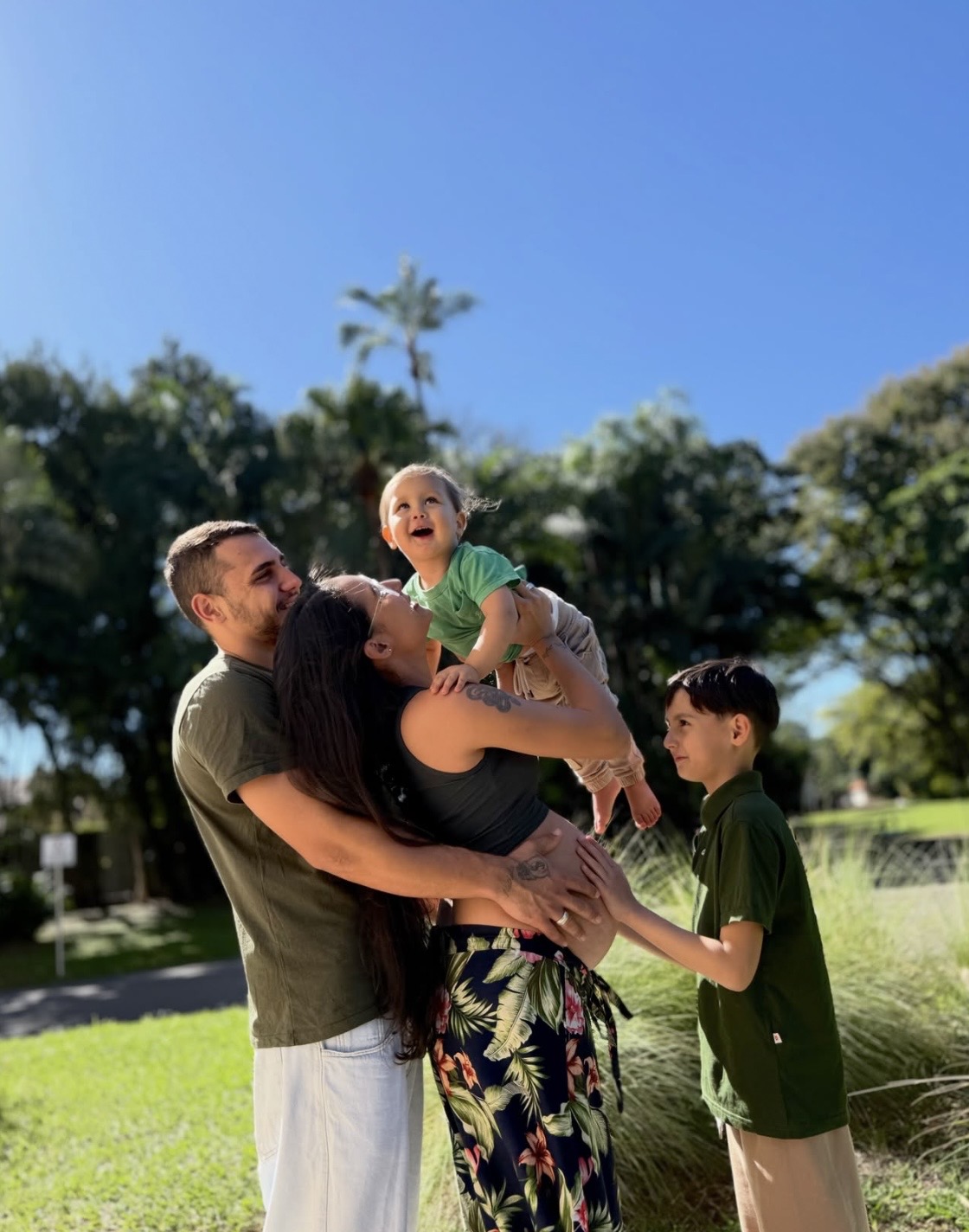 Família com duas crianças brincando ao ar livre em dia de sol
